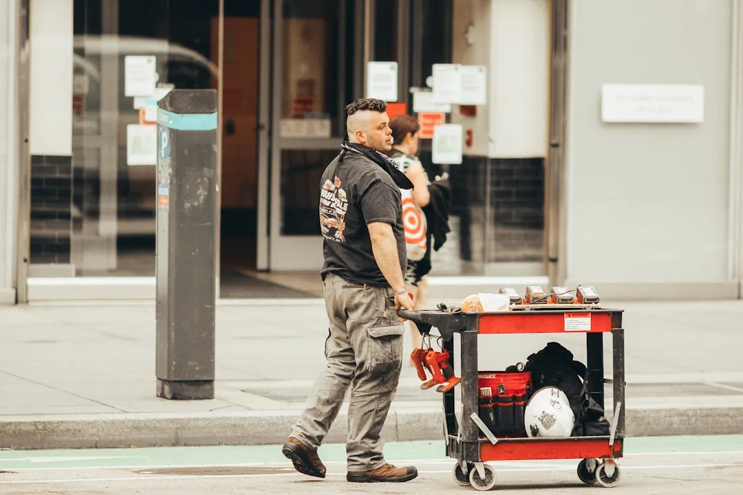 services-03 A professional cleaner in a red uniform holding a vacuum near a van, ready for service.